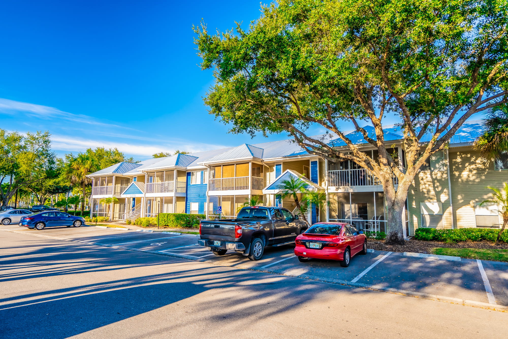 A red car is parked in front of a blue and white building.